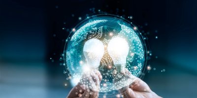 Two hands holding glowing light bulbs within a digital globe.