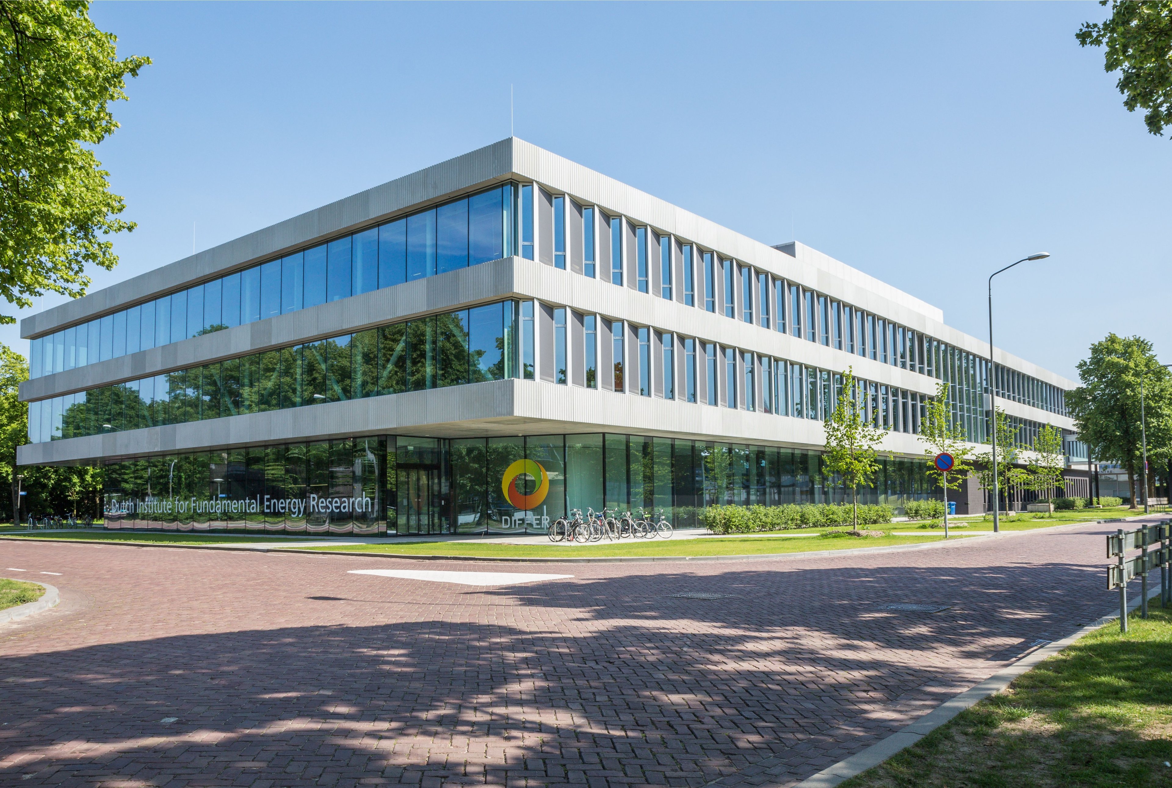 Dutch Institute for Fundamental Energy Research, a modern glass-walled building in daylight.