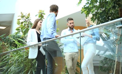 Young people brainstorming while standing against a glass railing.