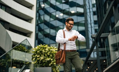 Business man looking at his watch in front of real estate buildings