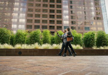 Businesspeople walking outside an office building, engaging in a conversation.