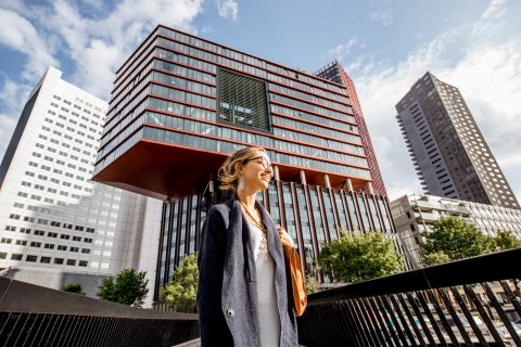 Woman dressed business casual in front of real estate building