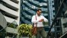 Business man looking at his watch in front of real estate buildings