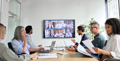 Group of colleagues having a hybrid meeting at work.