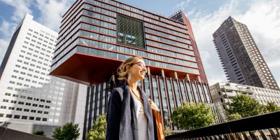 Woman dressed business casual in front of real estate building