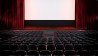 Empty filmtheatre with red curtains and white screen