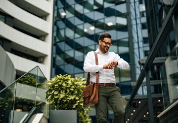Business man looking at his watch in front of real estate buildings