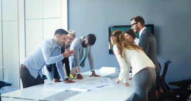 People having a group discussion around a meeting table about workplace management.