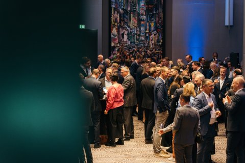 Business professionals networking and conversing during an indoor event reception.