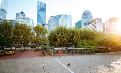 Tall skyscrapers at financial district of Paris with green parking lot in front.