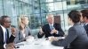 Business people gathering and discussing around a table in a meeting room.