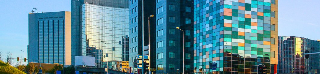 Glass midrise office building with colorful windows reflecting the sky.