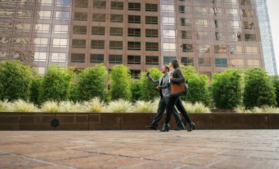 Businesspeople walking outside an office building, engaging in a conversation.