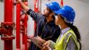 Two maintenance engineers looking at red pipes and valves.