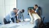 People having a group discussion around a meeting table about workplace management.