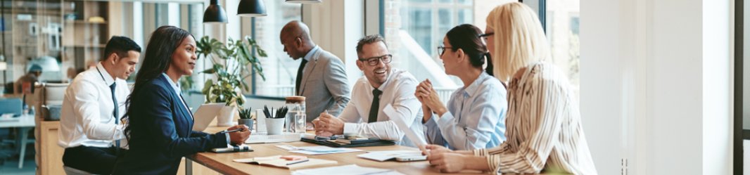 A group of diverse businesspeople smiling and discussing paperwork.