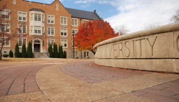 Real Estate building in autumn with University sign on the wall.
