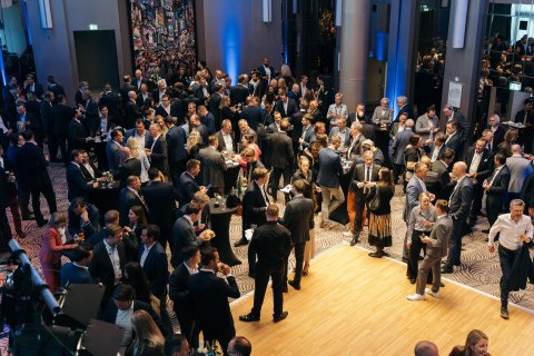 Large group of business attendees networking in a crowded event space.