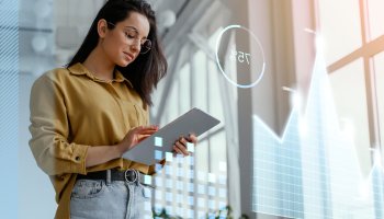 Woman using a tablet in a bright office with digital charts