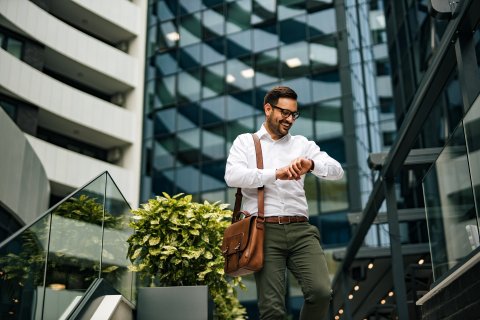 Business man looking at his watch in front of real estate buildings